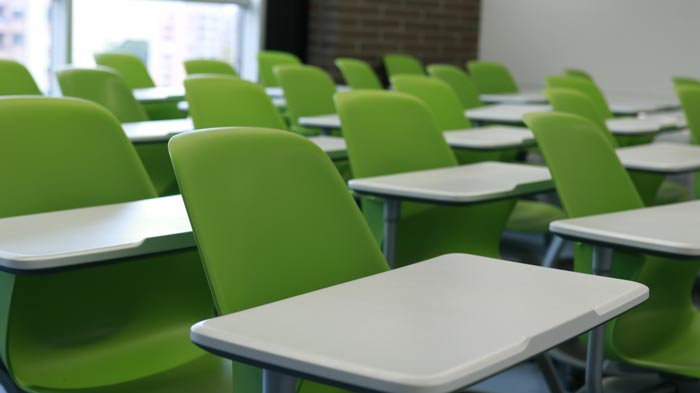 A classroom with green chairs and white desks arranged in rows, reflecting a modern learning environment.